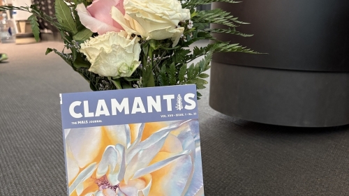 cover of the journal, purple and floral, in front of a bouquet of roses in the mals office 